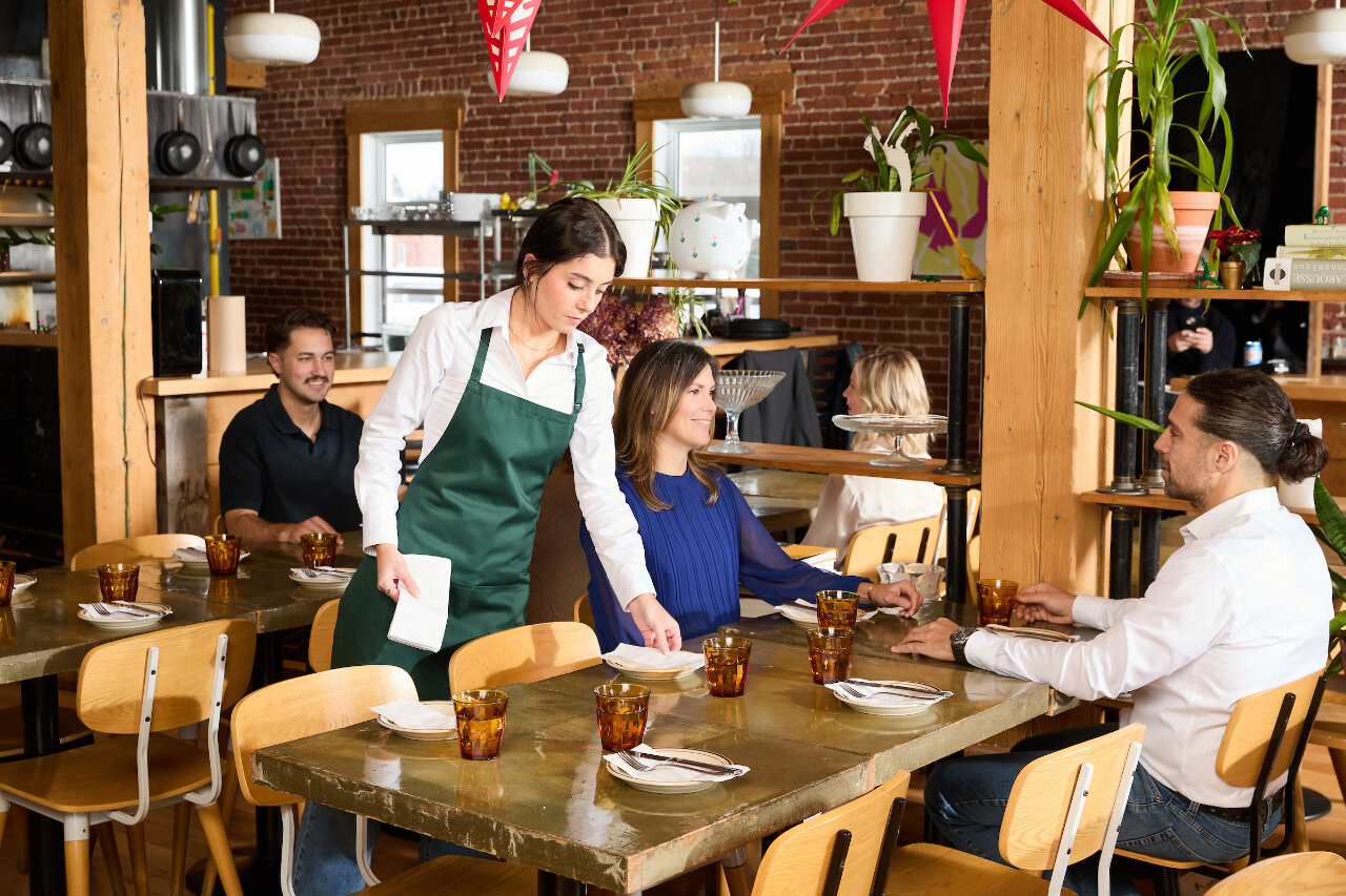 A server in a restaurant serving people and handling napkins